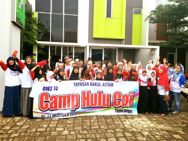 Children and volunteers with a Yayasan Darul Aitam banner at Camp Hulu Cai